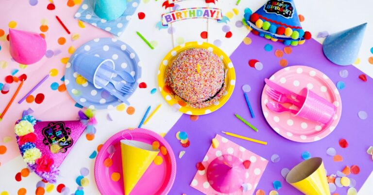 Colorful kids’ birthday party table with party hats, polka-dot plates, a sprinkle cake and confetti