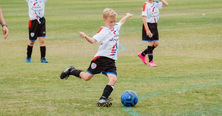 Young soccer player in a team uniform kicking the ball during a youth soccer game